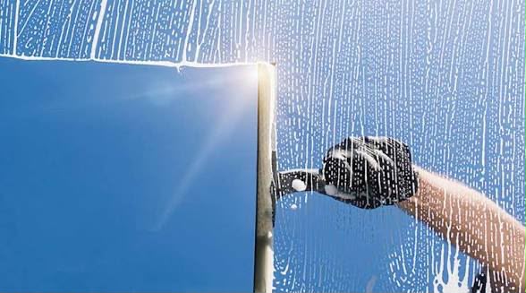 Professional window cleaning with squeegee and soapy glass